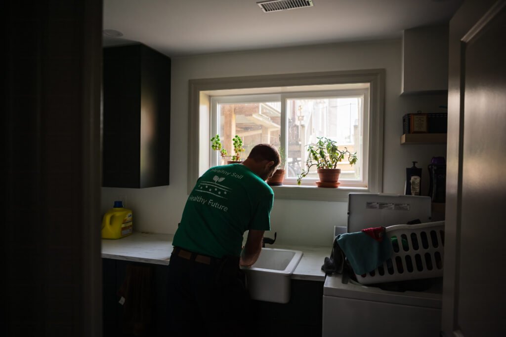 gordon alblas, member of the Ontario Soil Network, washes his hands in a dimly lit room after a busy morning on his farm in Brant County Ontario,