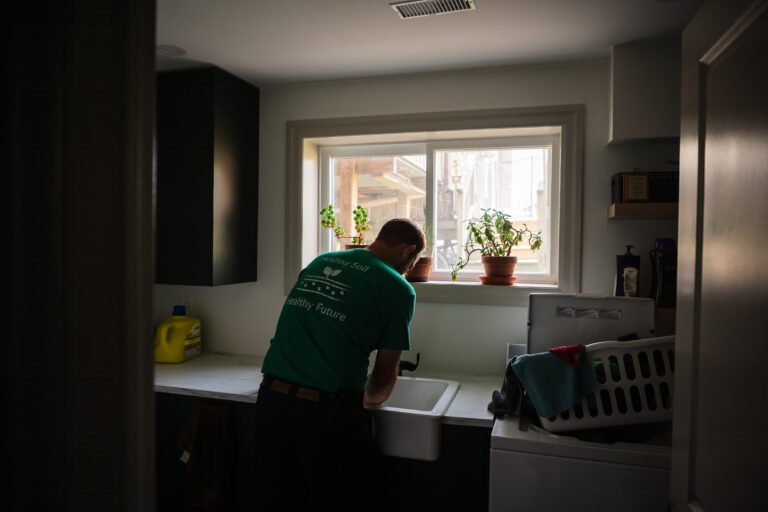 gordon alblas, member of the Ontario Soil Network, washes his hands in a dimly lit room after a busy morning on his farm in Brant County Ontario,