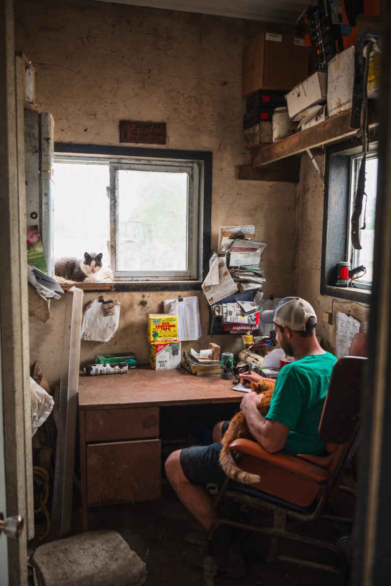 Gordon Alblas, OSN Farmer, sits in his father's office taking notes while petting his cat. Photographed by Ian Virtue